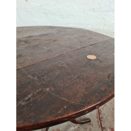 1188 - A Georgian oak circular tilt top tripod table - approx. 55cm high x 59cm in diameter