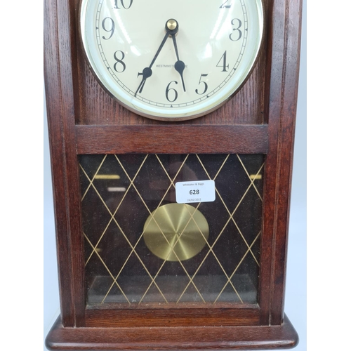 628 - A Staiger oak effect cased Westminster chime battery powered wall clock with pendulum - approx. 55cm... 