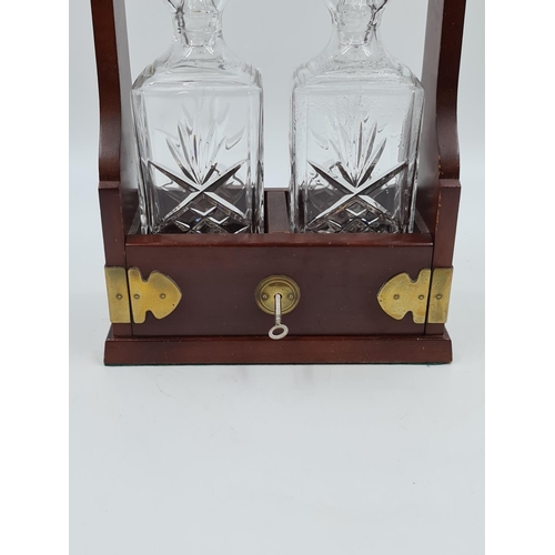 640 - A reproduction mahogany and brass two section tantalus with cut glass decanters - approx. 34cm high ... 