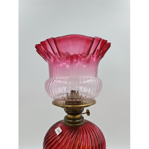 645 - A Victorian cranberry glass and brass oil lamp - approx. 46cm high