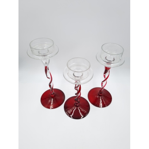 428 - Three graduating red and clear glass spiral candle holders - largest approx. 25cm high