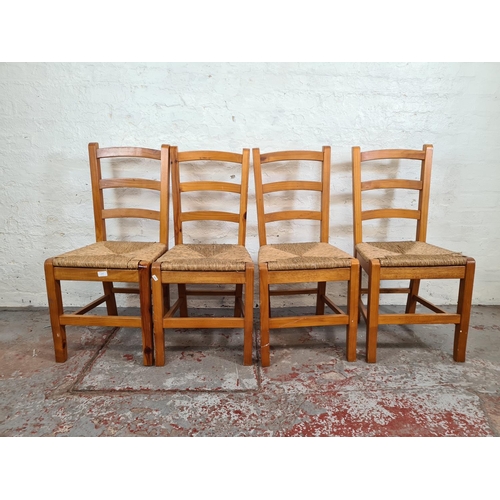 1115 - A set of four pine and rush seated ladder back dining chairs