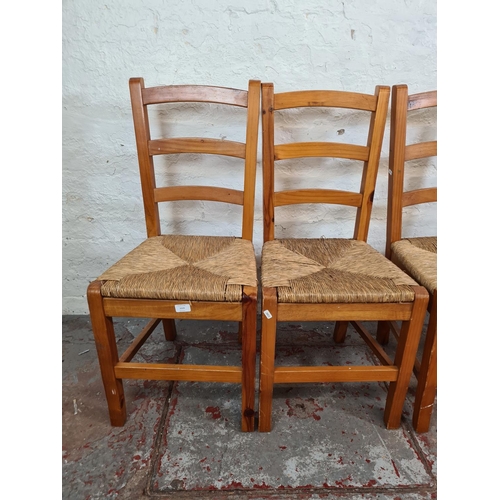 1115 - A set of four pine and rush seated ladder back dining chairs