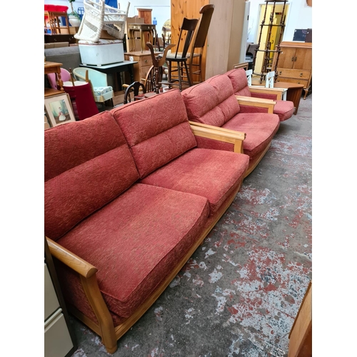 182 - An Ercol ash framed and red upholstered three piece lounge suite comprising three seater sofa, two s... 