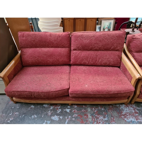 182 - An Ercol ash framed and red upholstered three piece lounge suite comprising three seater sofa, two s... 