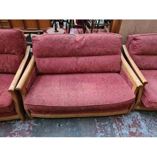 182 - An Ercol ash framed and red upholstered three piece lounge suite comprising three seater sofa, two s... 