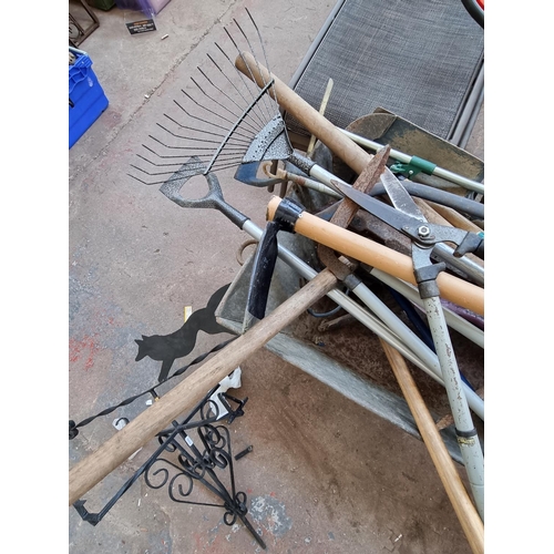 518 - A metal wheelbarrow containing a large collection of assorted gardening tools