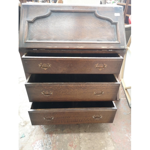 143 - A mid 20th century oak bureau with three drawers and fall front - approx. 100cm high x 76cm wide x 4... 