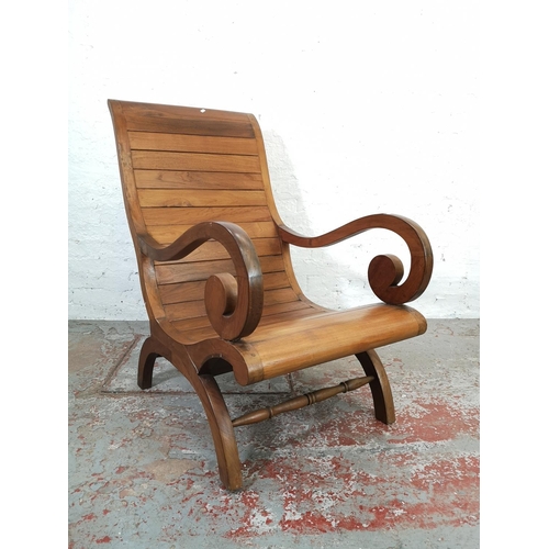 211 - An Indonesian solid teak plantation chair with matching stool - approx. 110cm high x 64cm wide x 76c... 