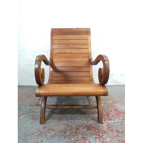 211 - An Indonesian solid teak plantation chair with matching stool - approx. 110cm high x 64cm wide x 76c... 