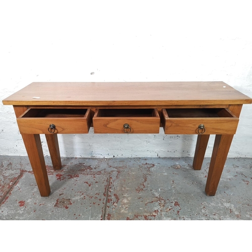 31 - An Indonesian teak three drawer console table - approx. 75cm high x 135cm wide x 40cm deep