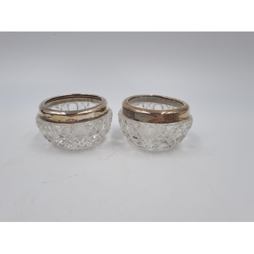 1042 - A boxed pair of cut glass salts with hallmarked Chester silver collars and two spoons, dated 1911