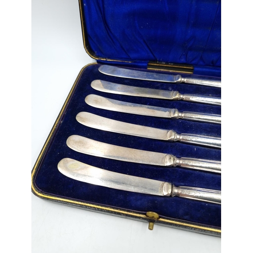 1043 - A cased set of six George V EPNS butter knives with hallmarked Sheffield silver handles, dated 1912