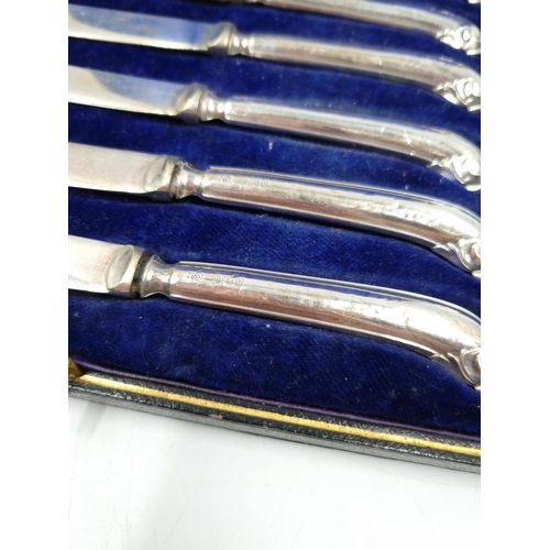 1043 - A cased set of six George V EPNS butter knives with hallmarked Sheffield silver handles, dated 1912