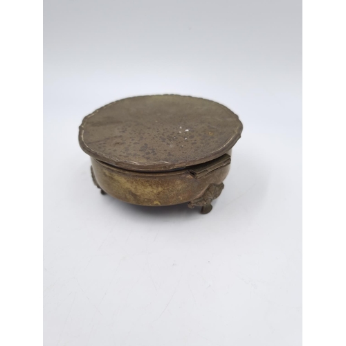 1047 - A vintage white metal circular tri footed trinket box with serial no. 830519 - approx. 9cm diameter ... 