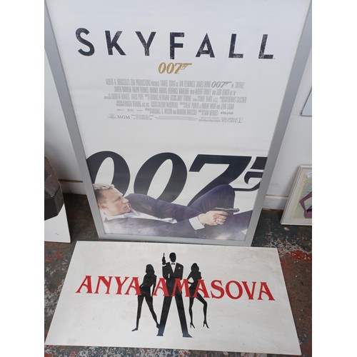 380 - Four James Bond items, one framed Skyfall poster, one two sided advertising board, one floor standin... 