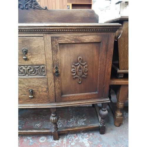 53 - An early 20th century carved oak sideboard with two central drawers, two outer cupboard doors and ba... 