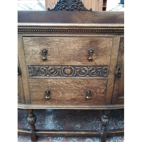 53 - An early 20th century carved oak sideboard with two central drawers, two outer cupboard doors and ba... 