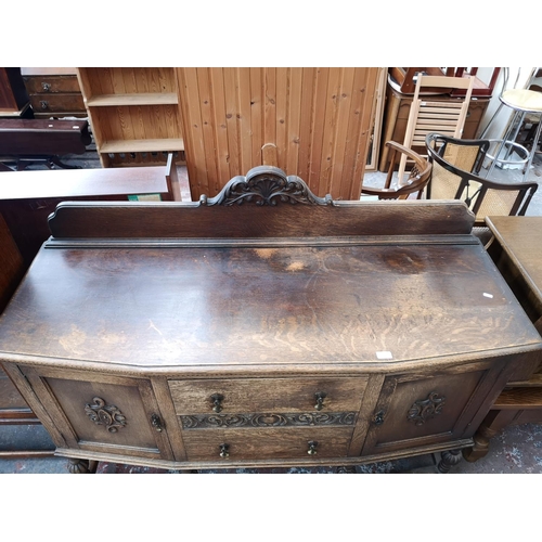 53 - An early 20th century carved oak sideboard with two central drawers, two outer cupboard doors and ba... 