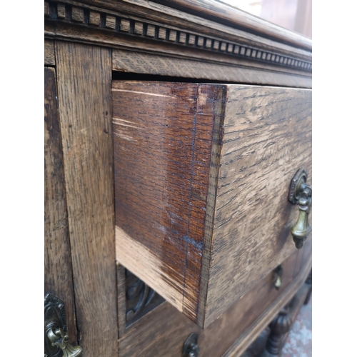 53 - An early 20th century carved oak sideboard with two central drawers, two outer cupboard doors and ba... 