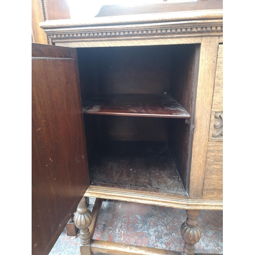 53 - An early 20th century carved oak sideboard with two central drawers, two outer cupboard doors and ba... 