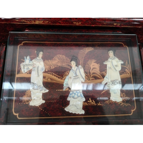 110 - An Oriental red lacquered nest of four tables with hand painted and mother of pearl Geisha girl desi... 