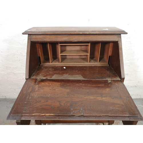 130 - An early 20th century Jacobean style geometric carved oak bureau with two drawers and fall front - a... 