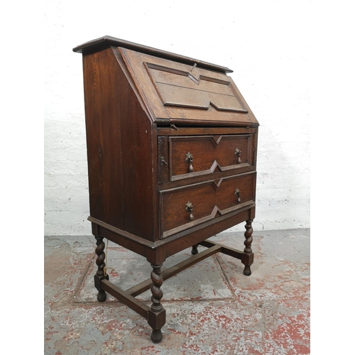 130 - An early 20th century Jacobean style geometric carved oak bureau with two drawers and fall front - a... 