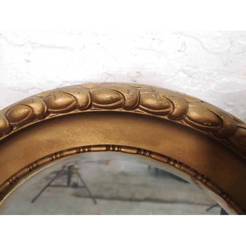 200 - A 19th century gilt framed oval bevelled edge wall hanging mirror - approx. 90cm wide x 65cm high