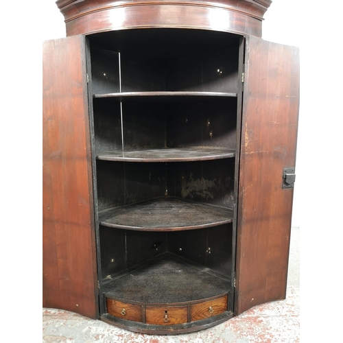 28 - A George III mahogany bow fronted wall hanging corner cabinet with brass 'H' hinges - approx. 112cm ... 