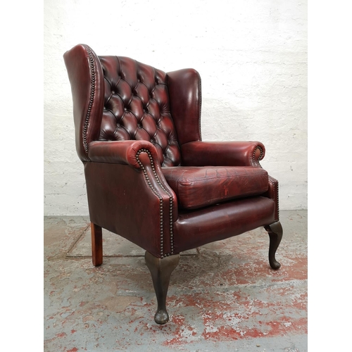 61 - An oxblood leather Chesterfield wing back armchair with cabriole supports - approx. 112cm high x 75c... 