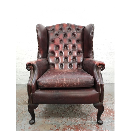 65 - An oxblood leather Chesterfield wing back armchair - approx. 112cm high x 77cm wide x 77cm deep