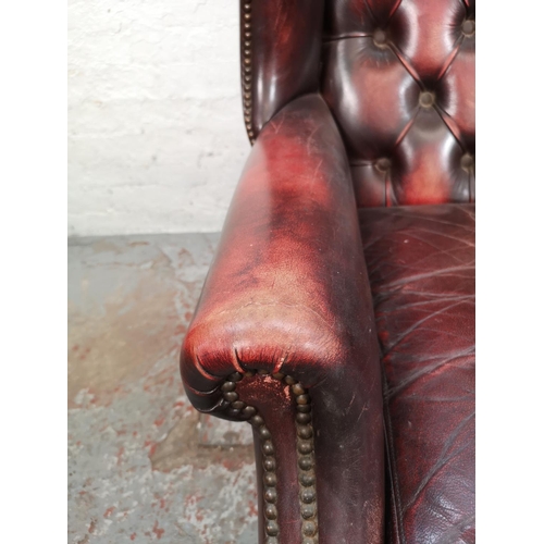 65 - An oxblood leather Chesterfield wing back armchair - approx. 112cm high x 77cm wide x 77cm deep