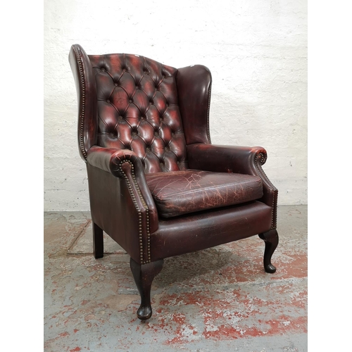 65 - An oxblood leather Chesterfield wing back armchair - approx. 112cm high x 77cm wide x 77cm deep