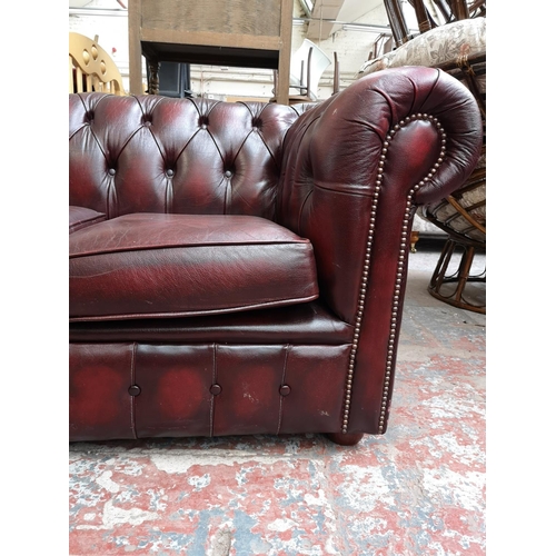 67 - An oxblood leather Chesterfield three seater sofa - approx. 72cm high x 195cm wide x 85cm deep