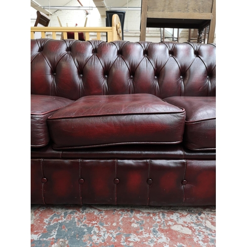 67 - An oxblood leather Chesterfield three seater sofa - approx. 72cm high x 195cm wide x 85cm deep