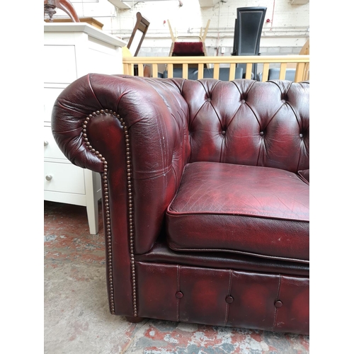 67 - An oxblood leather Chesterfield three seater sofa - approx. 72cm high x 195cm wide x 85cm deep