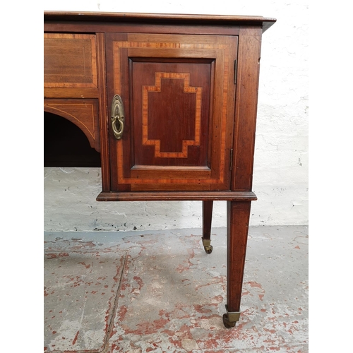 73 - An Edwardian inlaid mahogany desk with central drawer, two outer cupboard doors and tapering support... 