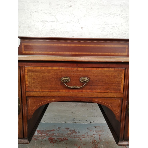 73 - An Edwardian inlaid mahogany desk with central drawer, two outer cupboard doors and tapering support... 