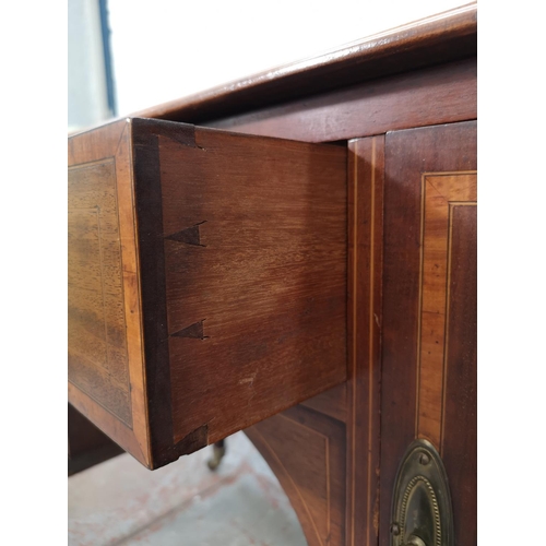 73 - An Edwardian inlaid mahogany desk with central drawer, two outer cupboard doors and tapering support... 