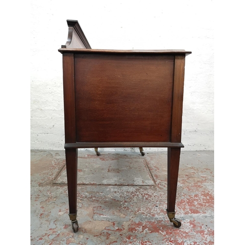 73 - An Edwardian inlaid mahogany desk with central drawer, two outer cupboard doors and tapering support... 