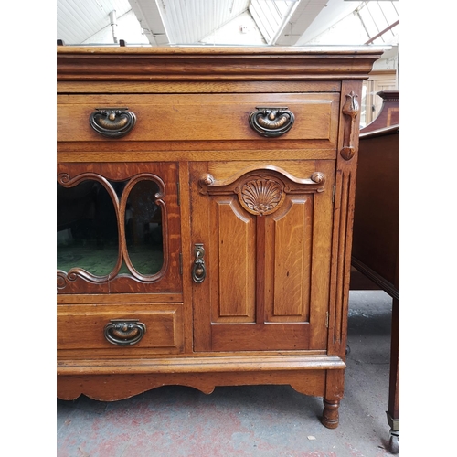 75 - An Art Nouveau oak sideboard with two upper drawers, two outer cupboard doors, central glazed door w... 