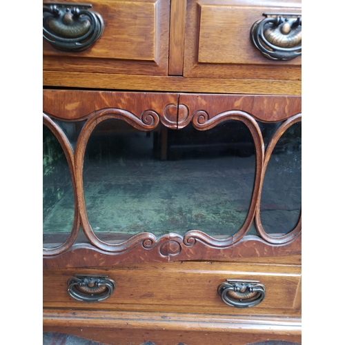 75 - An Art Nouveau oak sideboard with two upper drawers, two outer cupboard doors, central glazed door w... 