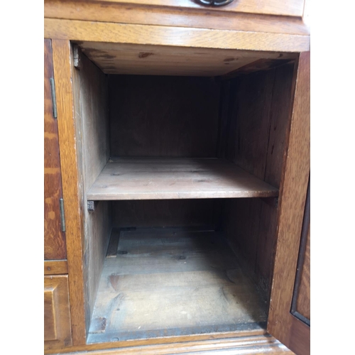 75 - An Art Nouveau oak sideboard with two upper drawers, two outer cupboard doors, central glazed door w... 