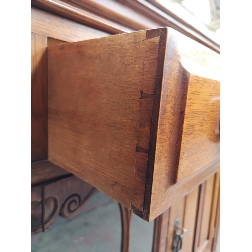 75 - An Art Nouveau oak sideboard with two upper drawers, two outer cupboard doors, central glazed door w... 