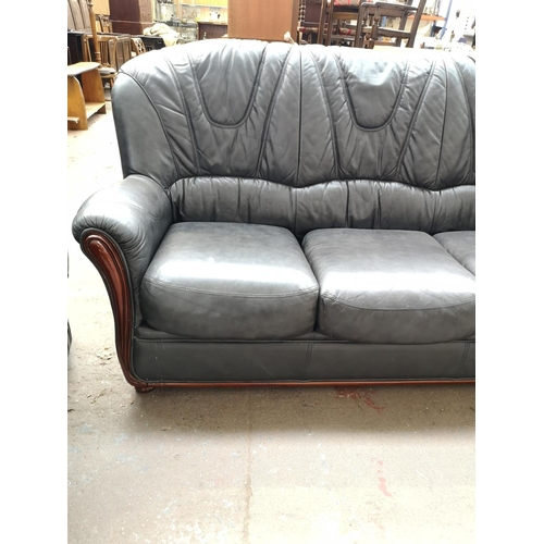 9 - A modern black leatherette three piece lounge suite comprising three seater sofa, armchair and elect... 