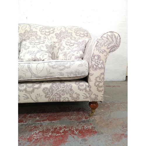 92 - A Wesley Barrell white and purple floral upholstered three seater sofa with castors - approx. 93cm h... 