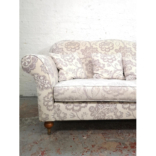 92 - A Wesley Barrell white and purple floral upholstered three seater sofa with castors - approx. 93cm h... 