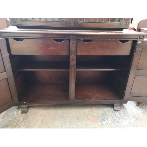 423B - An Ercol dark elm and beech court cupboard with two upper glazed doors and two lower cupboard doors ... 