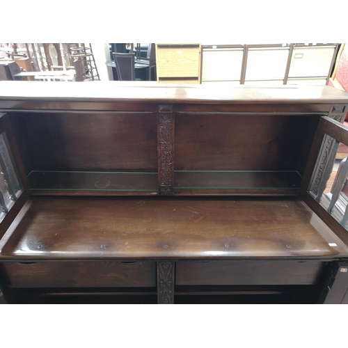 423B - An Ercol dark elm and beech court cupboard with two upper glazed doors and two lower cupboard doors ... 